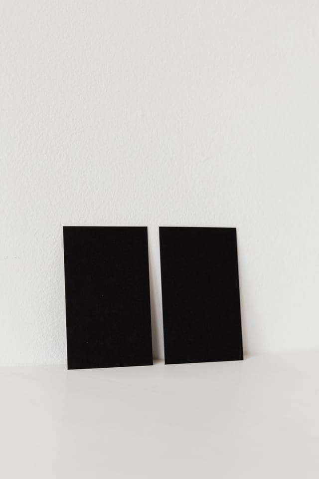 Dos tarjetas de presentación oscuras recargadas en un muro claro